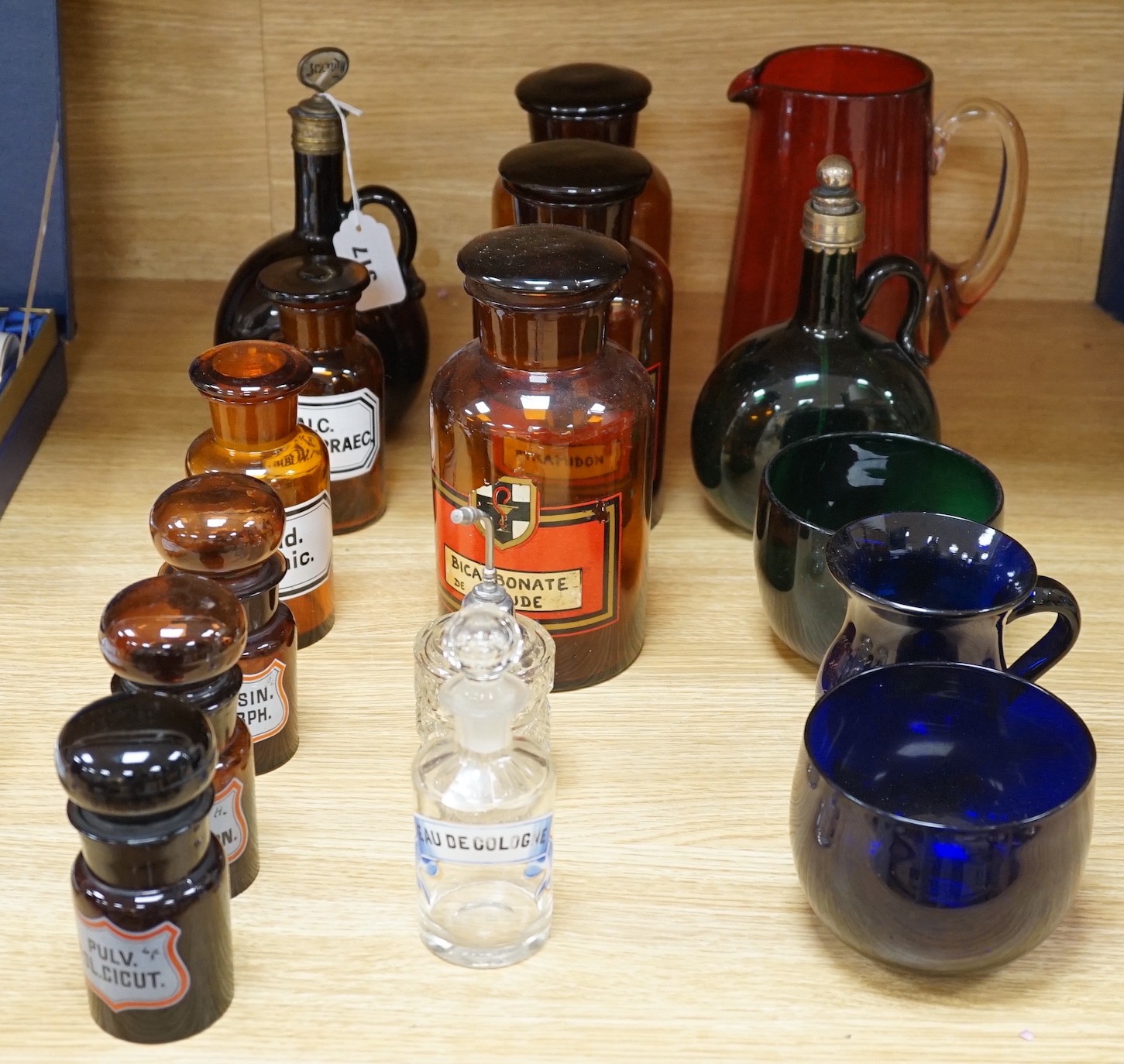 Nine glass chemist jars and covers, two decanters, two rinsers, and a cranberry jug and a mug, mostly coloured glass, jug 21 cm high